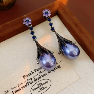 Detail of lavender pearl drop earrings with crystal flower studs and blue stones