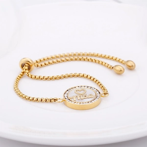 Macro shot of gold-plated bracelet with a round Mãe pendant and sparkling crystals