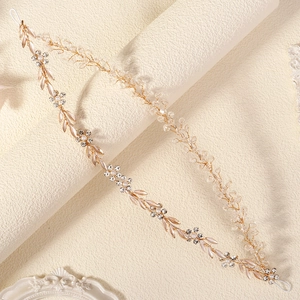 Detail of bridal hair vine with golden wire, white enamel leaves and crystal beads