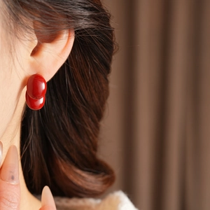 Nahaufnahme eleganter roter ovaler Ohrstecker im Retro-Stil an einem Modell