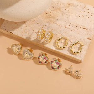 Set de boucles d'oreilles dorées avec cœurs en zircon et perles sur socle en pierre