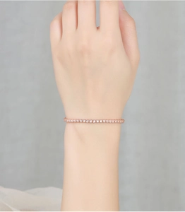Close-up of elegant rose gold tennis bracelet with small sparkling stones on female wrist