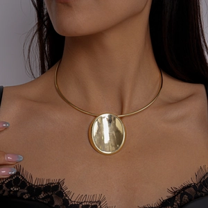 Detailaufnahme eines großen goldenen ovalen Anhängers mit Spiegelglanz an einem steifen Collier