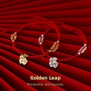 Detail of red woven zodiac horse bracelet with gold and silver charms on festive background