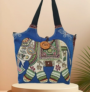 Detail der blauen Canvas-Tasche mit ethnischer Elefantenstickerei und großem Holzknopf