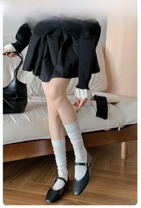 Close-up of white calf-length ribbed socks with black Mary Jane shoes for ballet style