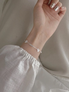 Close-up of S925 sterling silver bracelet with heart and cross charms on woman's wrist