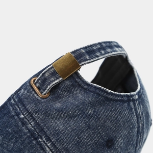 Detail of blue washed denim baseball cap with adjustable bronze metal buckle