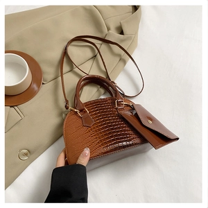 Detail of brown crocodile pattern shell bag with matching mini envelope pouch attachment