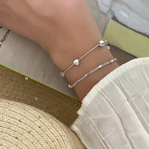 Detail of elegant silver double-layer heart bracelet worn with stylish summer attire
