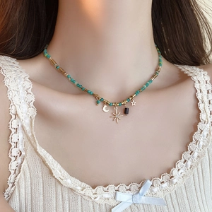 Detail of bohemian turquoise beaded necklace with gold crescent and star charms on neck