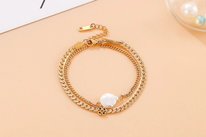 Detail of gold double-layer bracelet with shell pearl and black clover charm