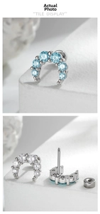 Detail of curved moon-shaped ear studs with zircon stones and screw back closure