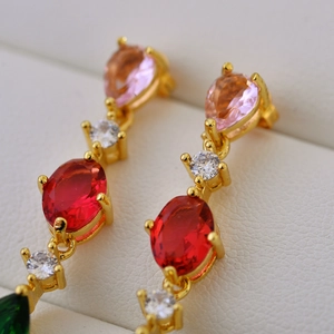 Macro view of multi-color teardrop gemstone earrings featuring gold prong settings