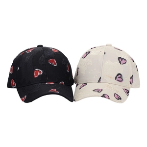 Detail of black and beige baseball caps with distressed fabric and heart print patterns