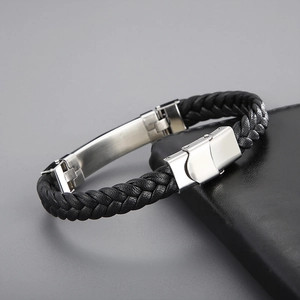 Macro view of woven black leather texture and brushed steel clasp on men's bracelet