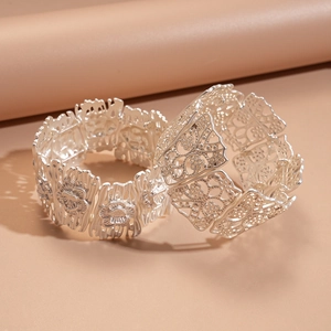 Detailed macro view of two matte silver openwork bracelets with intricate floral patterns