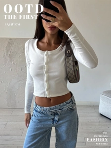 Close-up of white ribbed knit cropped cardigan with button closure and crew neck