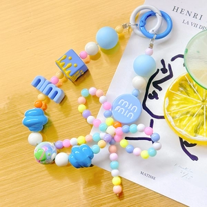 Close-up of colorful beaded phone strap with candy-colored resin beads on wooden desk