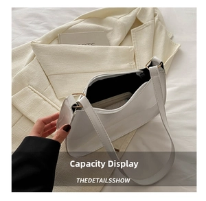 Interior view showing the capacity of a white glossy leather underarm bag on tweed