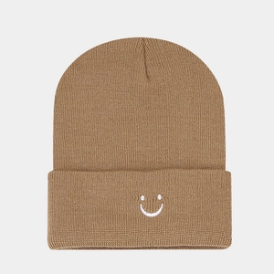 Close-up of brown knit beanie showing white embroidered smiley face on the folded cuff