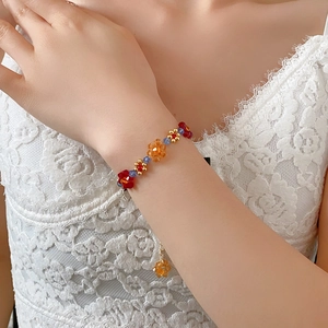 Gros plan d'un bracelet de fleurs en cristal coloré avec perles dorées et chaînette