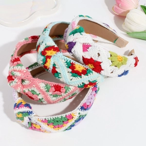 Close-up of four handmade knitted floral headbands with colorful embroidery and top knots