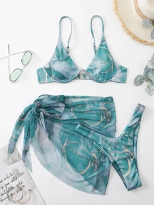 Flat lay of marble print bikini three-piece set with teal sarong and vacation props