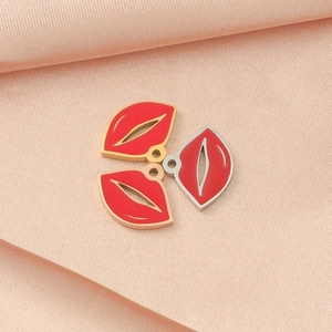 Macro view of lip-shaped enamel charms in gold and silver on pink silk fabric