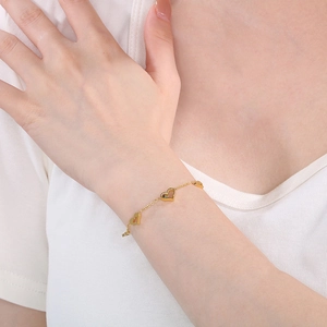 Detailed view of a gold heart link bracelet with sparkling zircon accents on a wrist