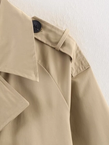 Detail of khaki trench coat featuring classic shoulder epaulettes and premium buttons