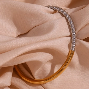 Detail of twisted cable and polished flat gold and silver stainless steel bangle
