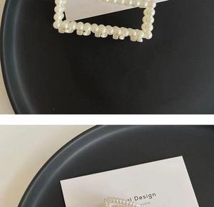 Detail of square woven pearl hair claw clip with elegant white beads on a tray