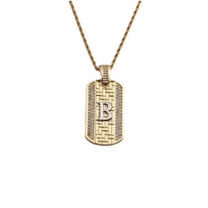 Détail du pendentif doré avec texture tressée, bordure en diamant et lettre B en argent