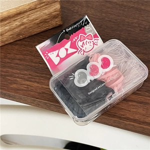 Macro detail of cream-colored elastic hair ties in a cartoon box on wooden surface
