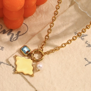Close-up of 18K gold plated O-chain necklace with blue gemstone and pearl pendant