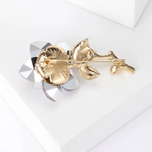Detailed view of elegant rose crystal brooch with gold metal stem and clear petals