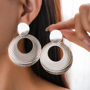Polished silver textured hoop earrings with small round studs worn by a female model