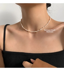 Close-up of small baroque freshwater pearl necklace worn by model on black jacket