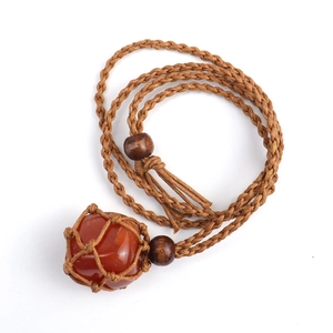 Detail of handcrafted brown net pouch holding a reddish-brown raw stone on a wooden bead cord