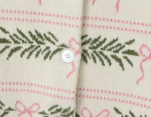 Detail of knit fabric with pink bow jacquard pattern and pearlescent button closure