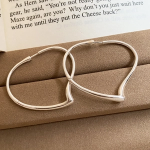 Macro shot of silver heart hoop earrings on a vintage book and velvet jewelry box