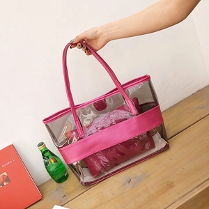 Transparent PVC tote beach bag with pink faux leather handles and inner pouch on wooden table