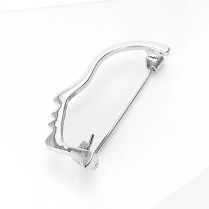 Detailed close-up of a silver abstract face profile brooch with a polished metallic finish