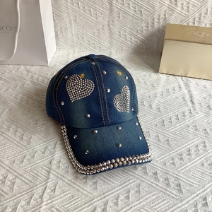 Close-up of heart rhinestone embellishments and metal studs on a denim baseball cap