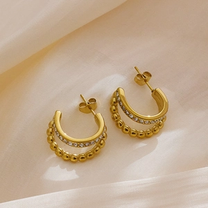 Detail of gold-plated double-layer C-shape earrings with zircons and beaded texture