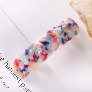 Detail of a rectangular acetate hair clip featuring colorful marbled textures and patterns