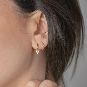 Close-up of gold geometric earrings set featuring triangle pendant and beaded crystal hoop