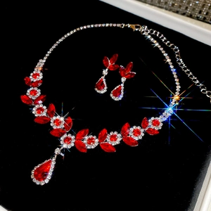 Detailed view of floral necklace and earrings set with red gems and sparkling crystals