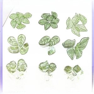 Detail view of green leaf-shaped glass beads with hole for DIY jewelry making